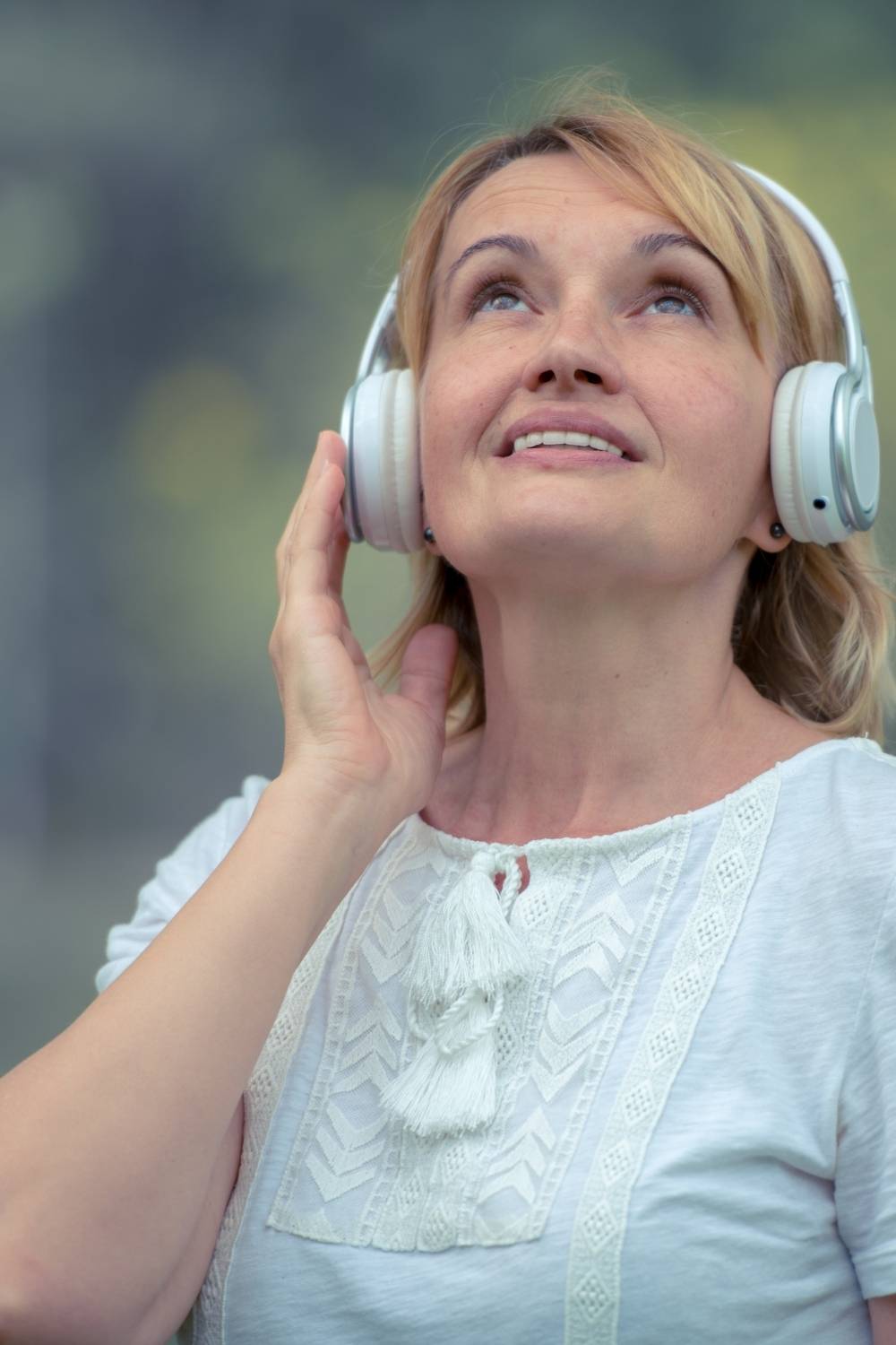 Frau hört bewusst Solfeggio Frequenzen über Kopfhörer und erlebt ein intensives Frequenzerlebnis je nach Ziel